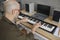 Man who loves to play music plays on modern synthesizer creating new musical composition.