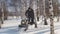 Man in winter clothes fast riding on mini snowmobile on deep snowdrifts in the forest and maneuvering between the trees