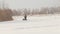 Man in winter clothes riding on mini snowmobile on deep snowdrifts in the field, walking with snow and waving his hands