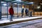 man at winter snowed night at railway station waiting for tram