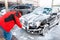 A man wipes a foam-covered black car with a brush at a self-service car wash. Front view