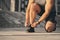 A man with wired headphones in a light athletic uniform ties a lace on a shoe for  running. Sport concept