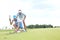 Man with woman aiming ball on golf course against sky