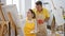 Man and woman artists kissing over coffee while drawing together in art studio classroom