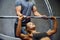 Man and woman with barbell flexing muscles in gym