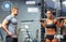 Man and woman with barbell flexing muscles in gym