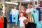 man and woman with boy choosing t-shirts and other goods in sport shop