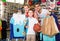 man and woman with boy choosing t-shirts and other goods in sport shop