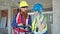 Man and woman builders talking on smartphone using touchpad at construction site