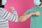 Man and woman bumping elbows to say hello on pink background, closeup. Keeping social distance during coronavirus pandemic