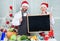 Man and woman chef santa hat near christmas tree hold blackboard copy space. Christmas recipe concept. Cooking christmas