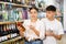 Man and woman choose high-quality alcoholic drink in supermarket