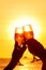 Man and woman clanging wine glasses with champagne at sunset