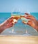 Man and woman clanging wine glasses with white wine at sea background