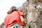 Man and woman climbing up on mountain cliff - Climber in action on the rock near the peak