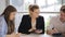 A man and a woman in, conduct business meetings, at a table against background of a large window.