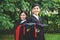 A man and woman couple dressed in black graduation gown or graduates with congratulations with graduation hats is standing