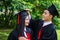 A man and woman couple dressed in black graduation gown or graduates with congratulations with graduation hats is standing,