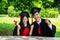 Man and woman couple dressed in black graduation gown or graduates with congratulations with hold diploma in hand is sitting