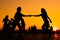 Man and woman couple silhouettes dancing against warm sunset orange sky