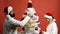 Man and woman decorate white Christmas tree with red balls on red background. Loving couple preparing for New Year party