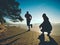 Man and woman do sports at lake against strong morning Sun