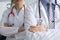 Man and woman doctors with phonendoscope around their necks stand with hands folded closeup