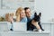 Man and woman drinking coffee and hugging their dog on kitchen table