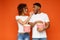 Man and woman eating popcorn on orange background