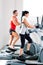 Man and woman with elliptical cross trainer at gym