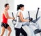 Man and woman with elliptical cross trainer at gym