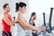 Man and woman with elliptical cross trainer at gym