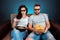 A man and a woman, a family watching a movie or a series in 3D glasses, a blue background. The concept of a cinema, films,