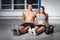 Man and woman - fitness team sitting on floor with kettlebells