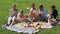 Man and woman with four kids having watermelon on picnic