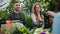 Man and woman giving organic food to customers taking money in farm market