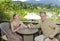 Man and the woman with glasses sit on a balcony overlooking rice terraces and mountains.