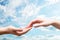 Man and woman hands touch in gentle, soft way on blue sunny sky