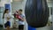 A man and woman having a boxing training in the gym - punching bag hanging on the foreground