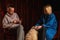 A man and a woman are having a dialogue. A dog is sitting next to him. Dark background. Conversation, reasoning, interview. Family