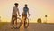A man and a woman in helmets with bicycles stand and talk at sunset. Rest after a bike ride on the highway. Track bikes