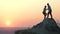 Man and woman hikers helping each other to climb stone at sunset in mountains. Couple climbing on high rock in evening nature. Tou