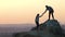 Man and woman hikers helping each other to climb stone at sunset in mountains. Couple climbing on high rock in evening nature. Tou