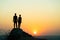 Man and woman hikers standing on a big stone at sunset in mountains. Couple together on a high rock in evening nature. Tourism,