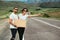 A man and a woman are hitchhiking. Wanderlust, autostop journey concept. Young people traveling hitchhiking. Hitchhiking couple