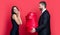 Man and woman hold gift. Elegant couple isolated on red. Exchange of gifts. Romantic day together. Love present for