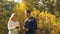 Man and woman holding and preparing to throw yellow leaves, having fun in park