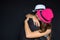 Man and woman hugging in hats on a black background. Strong embrace.