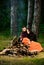 Man with woman hugs and warming up near bonfire. Young couple with tired faces covered with plaid.