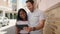 Man and woman interracial couple standing together using touchpad at street
